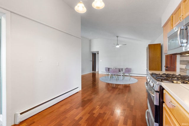 kitchen featuring light brown cabinetry, stainless steel appliances, baseboard heating, ceiling fan, and hardwood / wood-style floors