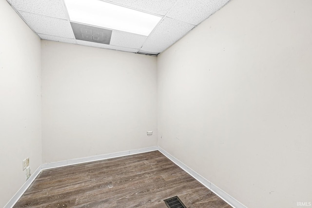 spare room with a paneled ceiling and dark hardwood / wood-style floors