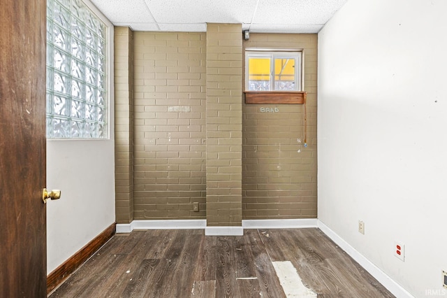 empty room with a paneled ceiling and dark hardwood / wood-style flooring