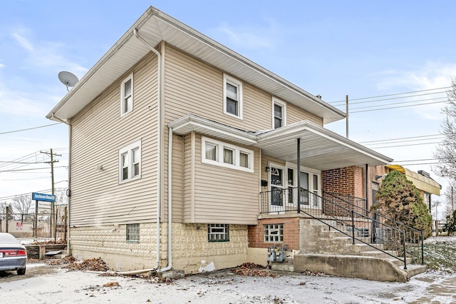 snow covered property with covered porch