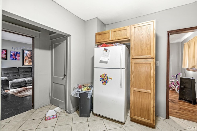 kitchen with light brown cabinetry, light tile patterned floors, and white refrigerator