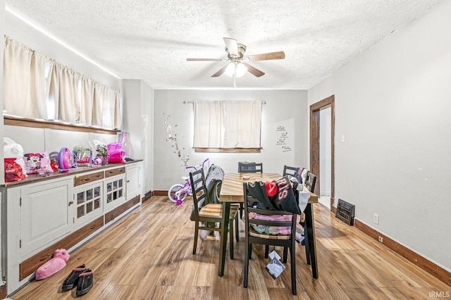 dining room with a textured ceiling, light wood-type flooring, and ceiling fan