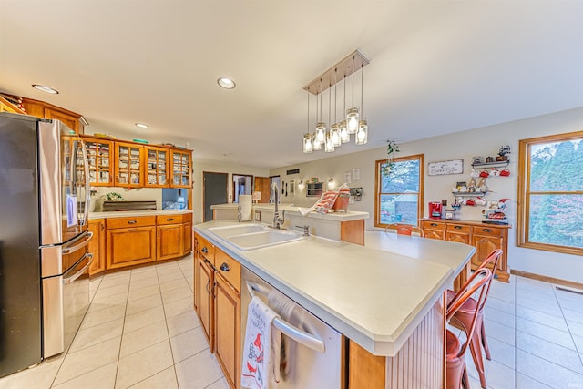 kitchen with appliances with stainless steel finishes, a breakfast bar, sink, light tile patterned floors, and a center island with sink