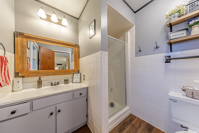 bathroom with an enclosed shower, vanity, hardwood / wood-style flooring, tile walls, and toilet