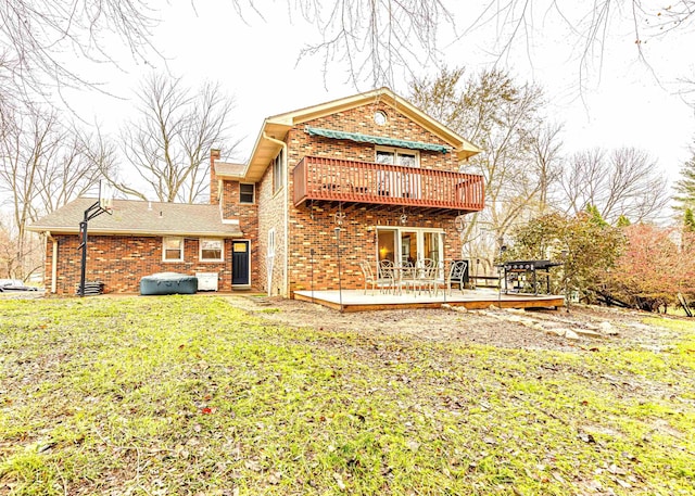 back of house with a hot tub, a balcony, a deck, and a lawn