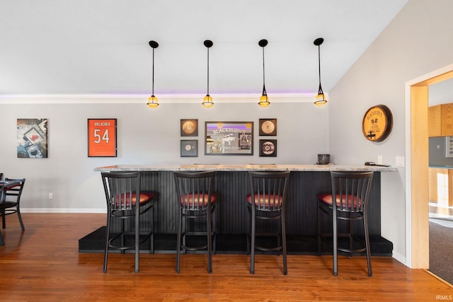 bar with vaulted ceiling, hardwood / wood-style floors, decorative light fixtures, and ornamental molding