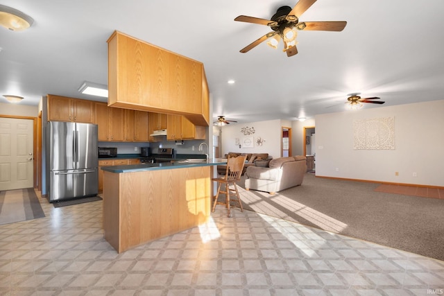 kitchen with sink, a kitchen breakfast bar, kitchen peninsula, light carpet, and appliances with stainless steel finishes