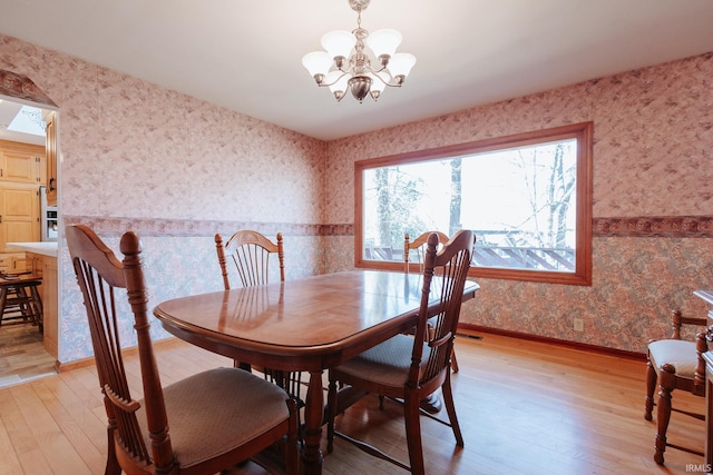 dining space with light wood-type flooring and an inviting chandelier