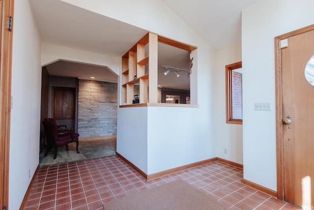 foyer with tile patterned flooring, rail lighting, and lofted ceiling