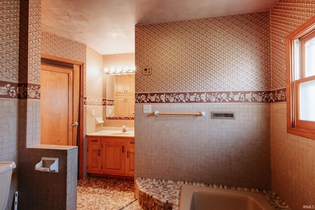 bathroom with tile patterned floors, vanity, tile walls, and a tub