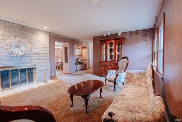 carpeted living room with an inviting chandelier, track lighting, a stone fireplace, and plenty of natural light