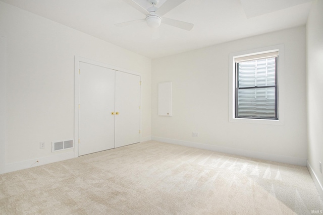 unfurnished bedroom featuring a closet, light colored carpet, and ceiling fan