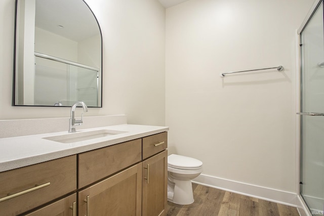 bathroom with hardwood / wood-style floors, vanity, toilet, and walk in shower