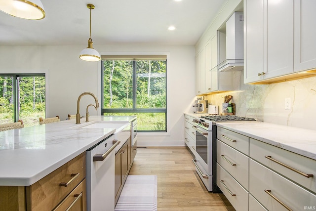 kitchen with white cabinetry, wall chimney exhaust hood, light stone counters, dishwashing machine, and stainless steel stove