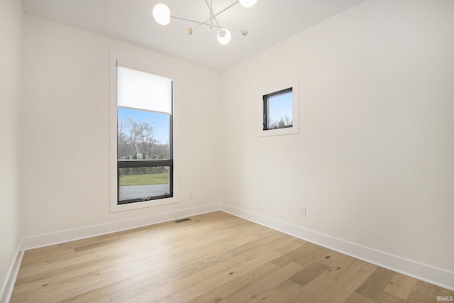 empty room featuring a chandelier and light hardwood / wood-style flooring