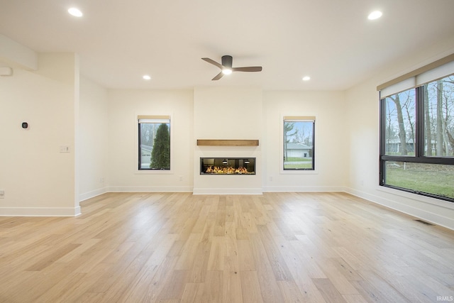 unfurnished living room with light hardwood / wood-style flooring, ceiling fan, and a healthy amount of sunlight