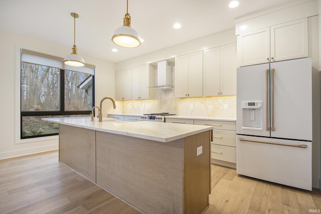 kitchen with wall chimney range hood, white cabinets, light hardwood / wood-style floors, and white refrigerator with ice dispenser