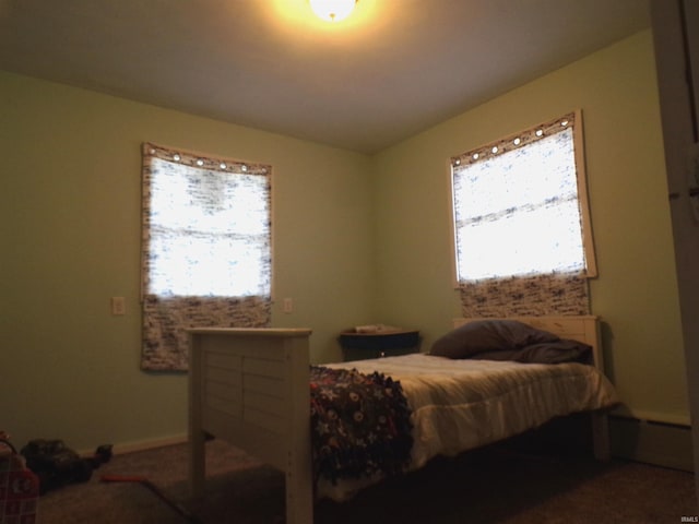 carpeted bedroom with a baseboard heating unit and multiple windows