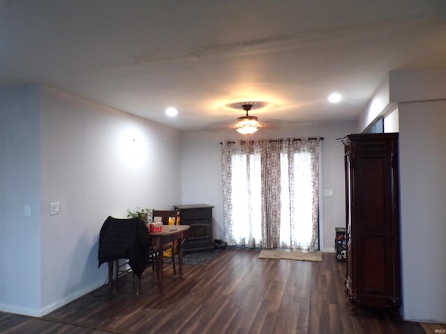 dining space featuring a wood stove, ceiling fan, and dark hardwood / wood-style flooring