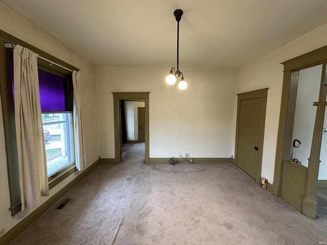 carpeted spare room with a chandelier