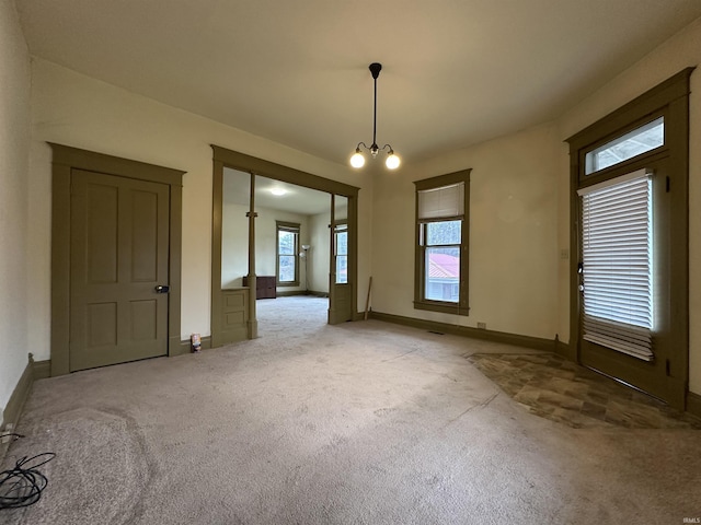 carpeted spare room featuring a chandelier