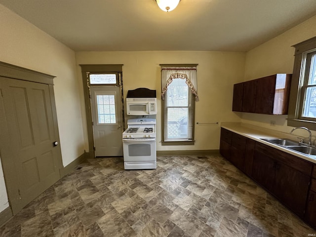 kitchen featuring dark brown cabinets, white appliances, sink, and a wealth of natural light