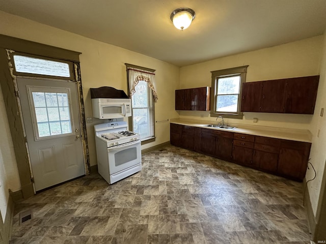 kitchen with dark brown cabinets, white appliances, and sink