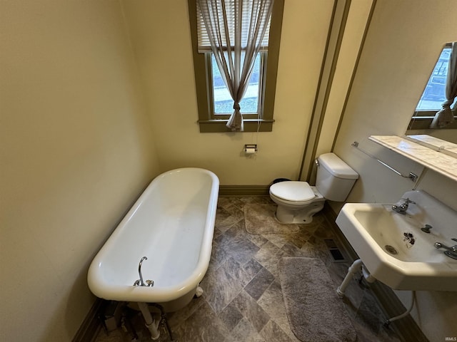 bathroom featuring a tub to relax in, toilet, and sink