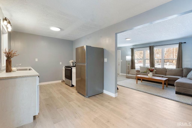 kitchen featuring sink, light wood-type flooring, a textured ceiling, and appliances with stainless steel finishes