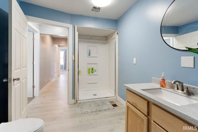 bathroom with vanity, toilet, wood-type flooring, and walk in shower