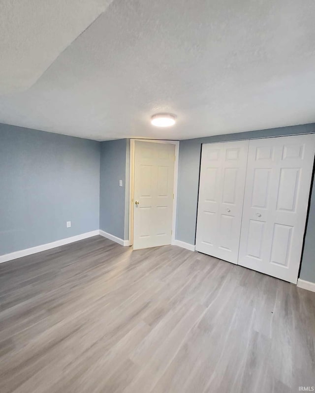 basement featuring wood-type flooring and a textured ceiling