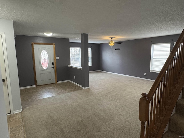 foyer with a textured ceiling, light colored carpet, and a healthy amount of sunlight