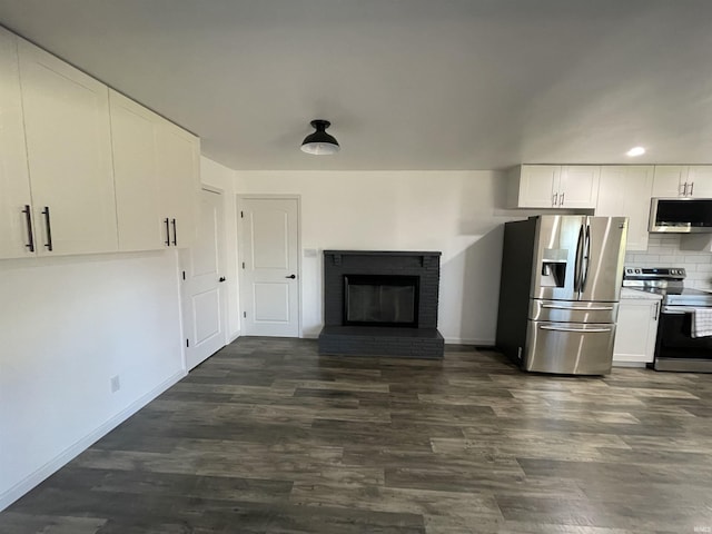 kitchen featuring white cabinets, a fireplace, backsplash, and stainless steel appliances