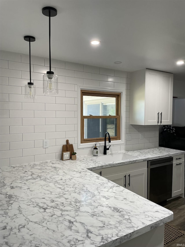 kitchen featuring sink, hanging light fixtures, light stone counters, stainless steel dishwasher, and white cabinets