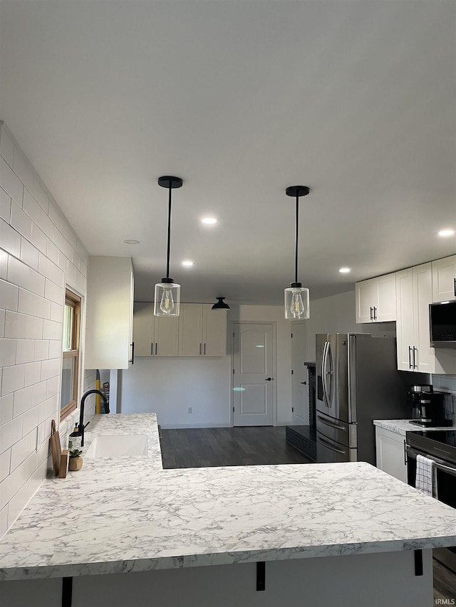 kitchen with appliances with stainless steel finishes, dark hardwood / wood-style flooring, sink, decorative light fixtures, and white cabinets