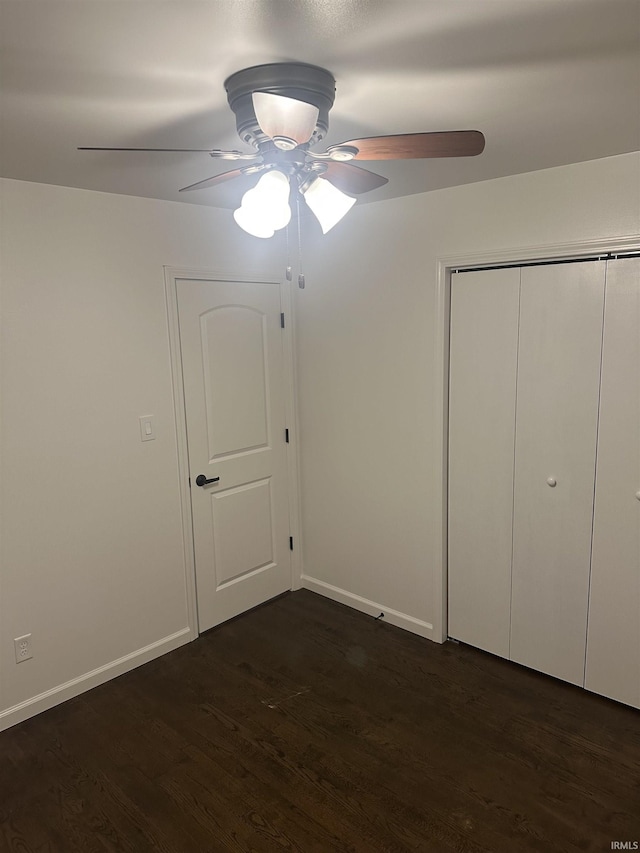 unfurnished bedroom with ceiling fan, dark hardwood / wood-style floors, and a closet