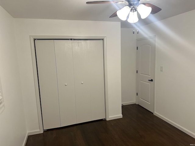 unfurnished bedroom with ceiling fan, dark hardwood / wood-style flooring, and a closet