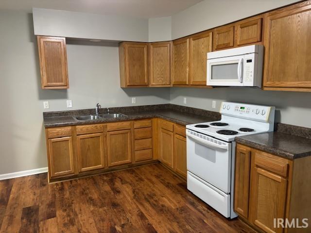 kitchen featuring white appliances, dark wood-type flooring, and sink