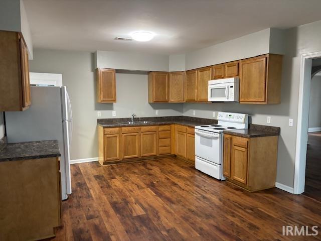 kitchen with dark hardwood / wood-style flooring, white appliances, and sink