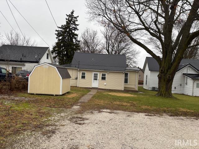 rear view of property with a lawn and a storage shed