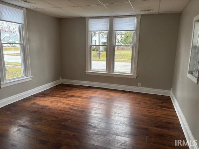 unfurnished room with a paneled ceiling and dark hardwood / wood-style floors