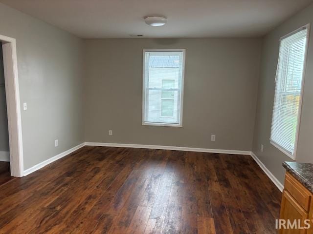 spare room with plenty of natural light and dark hardwood / wood-style floors