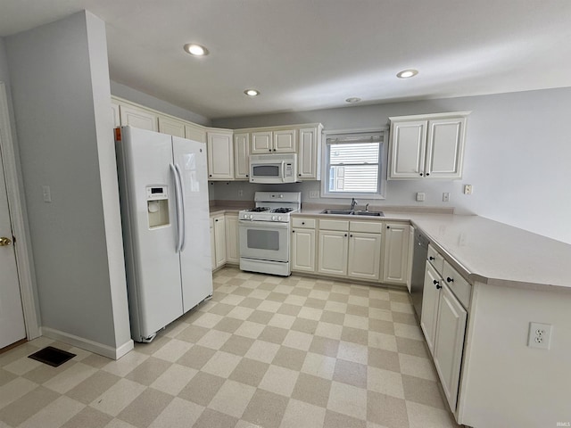 kitchen featuring white cabinetry, white appliances, kitchen peninsula, and sink