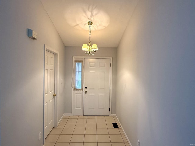 entryway with vaulted ceiling, light tile patterned floors, and an inviting chandelier