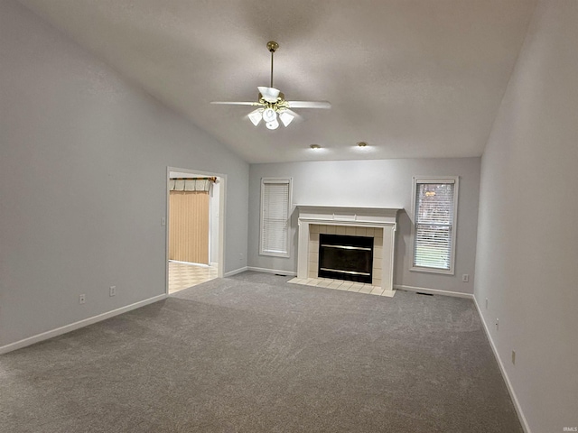 unfurnished living room featuring ceiling fan, lofted ceiling, a fireplace, and light carpet