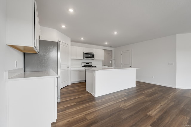 kitchen featuring white cabinets, appliances with stainless steel finishes, dark hardwood / wood-style flooring, and an island with sink