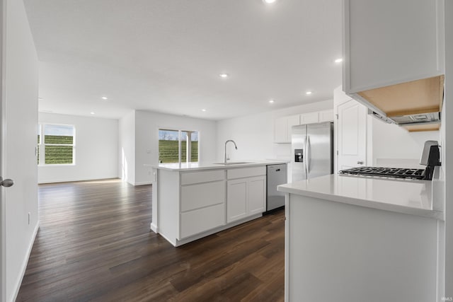 kitchen with appliances with stainless steel finishes, dark hardwood / wood-style flooring, sink, white cabinetry, and an island with sink