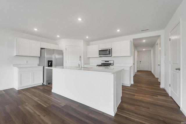 kitchen with a center island with sink, white cabinets, sink, appliances with stainless steel finishes, and dark hardwood / wood-style flooring