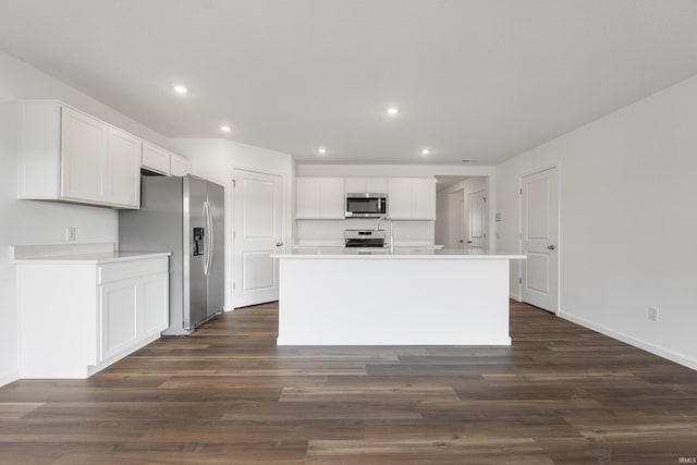 kitchen with white cabinets, appliances with stainless steel finishes, dark hardwood / wood-style floors, and an island with sink