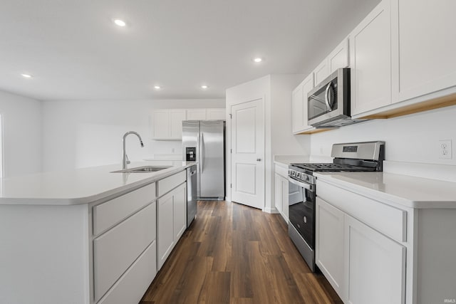 kitchen featuring dark wood-type flooring, white cabinets, a center island with sink, sink, and stainless steel appliances